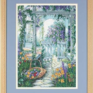 May include: A framed cross-stitch embroidery depicting a garden scene with a stone path leading through a wooden arbor covered in purple wisteria. A woven basket filled with colourful flowers sits on the path, surrounded by yellow and purple blooms.