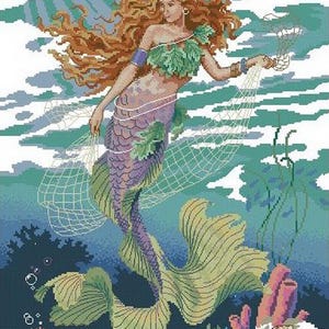 Puede incluir: Un patrón de punto de cruz que representa a una sirena con largo cabello castaño rojizo, vistiendo un top de hojas verdes. La sirena tiene una cola escamosa morada y verde, sostiene una red de pesca blanca y está rodeada de corales y algas.