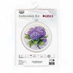 May include: An embroidery kit showing a cross-stitch design of a purple hydrangea flower with green leaves. The kit includes a round embroidery hoop and is packaged in a white plastic sleeve. The text "Embroidery Kit" and "Hydrangea" are visible.