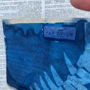 May include: A blue and white envelope with a "Par Avion Luftpost" stamp. The envelope has a blue watercolour wash and handwritten text in black ink.
