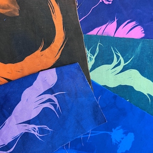 Pode incluir: Uma pilha de quadrados de tecido com diferentes fundos coloridos e desenhos impressos. Os desenhos incluem uma flor, um redemoinho e um ramo. O tecido é azul claro, azul escuro, verde, rosa e preto.