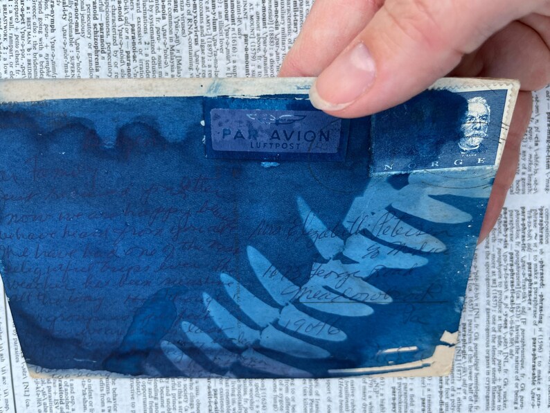 May include: A blue envelope with a "PAR AVION LUFTPOST" stamp. The envelope features a fern leaf design and handwritten text in blue ink. The text reads "Norsk Ti-Felis 18.7.1946 To Grandma 1946".