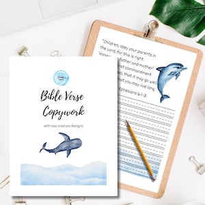 May include: Bible verse copywork with sea creature designs. The image shows two pages, one with text and a dolphin illustration, and the other with the text "Bible Verse Copywork" and a dolphin illustration. A pencil and a clipboard are also visible.
