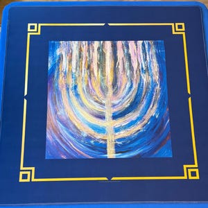 May include: A square, blue table cover with a gold border and corner accents. The center features a colorful abstract painting with a central vertical gold line. The table cover is likely designed for a game or activity.