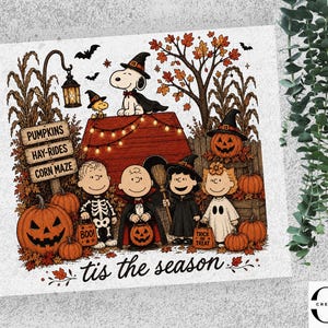 May include: A graphic print featuring Peanuts characters in Halloween costumes standing by a doghouse. Text reads PUMPKINS, HAY-RIDES, CORN MAZE, BOO!, TRICK OR TREAT, and tis the season. Snoopy wears a witch hat, and friends are dressed as a skeleton, vampire, witch, and ghost.
