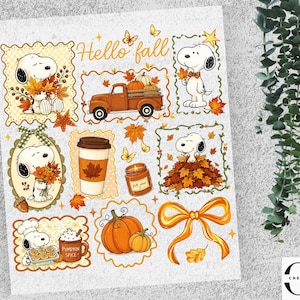 May include: A sticker sheet featuring Snoopy in various autumn scenes, including holding fall leaves, sitting in a pile of leaves, and baking. The sheet includes a pumpkin-filled truck, a coffee cup, a candle, pumpkins, and a bow, with the text Hello fall.