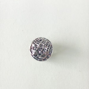 May include: A silver-coloured, spherical bead with a detailed, openwork design. The bead's surface features a repeating geometric pattern, creating a textured appearance. The bead is likely used for jewellery making or crafting.