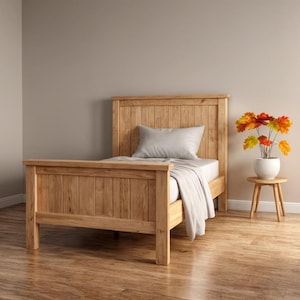 May include: A wooden bed frame with a headboard and footboard. The bed is made of light-colored wood and has a simple, rustic design. A gray pillow and white bedding are on the bed. A small wooden side table holds a vase of colorful flowers.