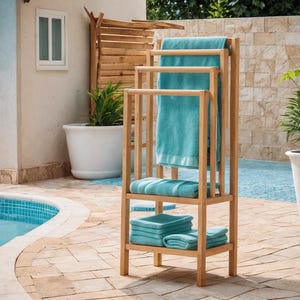May include: A wooden towel rack with three levels, holding several folded and hanging turquoise towels. The rack is made of light-colored wood and is positioned outdoors near a pool.