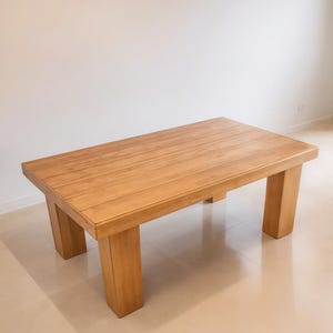 May include: A rectangular wooden coffee table with a light brown finish. The table has a simple design with four thick, square legs. The table measures approximately 48 inches long, 24 inches wide, and 16 inches high.
