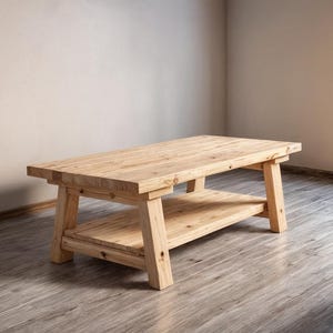 May include: A rectangular, light-colored wooden coffee table with a lower shelf. The table has a natural wood grain finish and sturdy, angled legs. The table measures approximately 48 inches long, 24 inches wide, and 18 inches high.