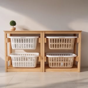 May include: A wooden storage unit with four rectangular laundry baskets. Two baskets are white, and two are beige. The unit has a natural wood finish and a small potted plant on top. The baskets are designed for organizing laundry.