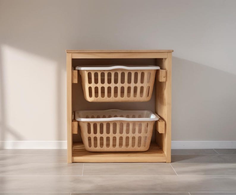 May include: A wooden storage unit with two beige laundry baskets. Each basket has a rectangular shape with a white rim and a grid pattern of vertical slots. The unit is made of light-colored wood.