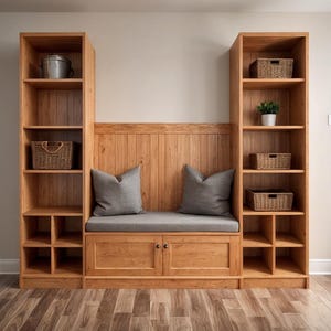May include: A wooden storage unit with a built-in bench, shelves, and cabinets. The unit is made of light-colored wood and features a bench with gray cushions and two gray pillows. Woven baskets and a metal bucket are displayed on the shelves.