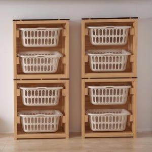 May include: Two wooden laundry sorters, each with three white plastic baskets. The sorters are made of light-colored wood and have a simple, rectangular design. The baskets are rectangular with a slotted design.