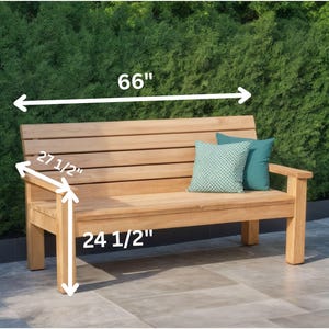May include: A wooden outdoor bench with a natural finish. The bench is 66 inches long, 27.5 inches high, and 24.5 inches deep. Two decorative pillows in teal and patterned green are on the bench.