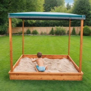 May include: A wooden sandbox with a green canopy, set on a grassy lawn. The sandbox has a rectangular shape with a wooden frame and is filled with sand. A child is sitting inside the sandbox.