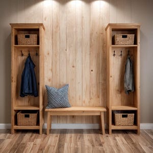 Puede incluir: Unidad de almacenamiento de entrada de madera con dos armarios altos y un banco. Cada armario tiene un estante con una cesta tejida, ganchos para abrigos y un estante inferior con otra cesta. Una chaqueta vaquera azul y una chaqueta gris cuelgan de los ganchos.