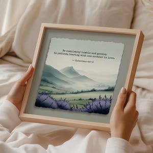 Puede incluir: Una impresión enmarcada con un paisaje de acuarela con montañas y lavanda. La impresión incluye el texto "Be completely humble and gentle; be patient, bearing with one another in love. -- Ephesians 4:2-3."