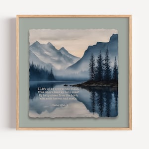 May include: A framed watercolour print depicting a tranquil landscape with mountains, a lake, and trees. The artwork uses shades of blue and grey, with text from Psalm 121:1-2. The frame is a light wood colour.