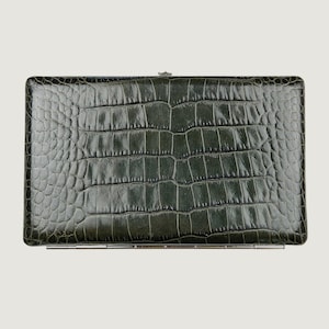 May include: A rectangular dark green clutch with a glossy finish and a textured crocodile skin pattern. The accessory features a metallic silver hinge along the bottom edge and a small metallic clasp centered on the top edge of the frame.