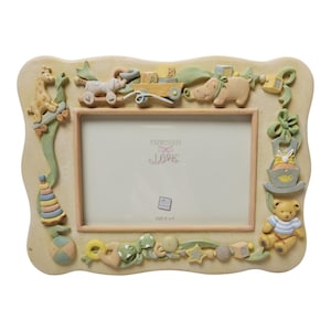 May include: A beige picture frame with a light pink interior. The frame is decorated with 3D baby-themed toys, including a giraffe, hippo, and teddy bear. The frame has the text "EXPRESSION LOVE" and is sized 12.7cm x 10.16cm.