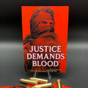 May include: A red graphic print with the text "JUSTICE DEMANDS BLOOD" and an illustration of a person with a blindfold and beard. Several gold-coloured bullets are in front of the print.