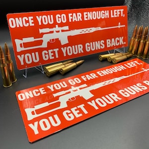 May include: Two red rectangular signs with white text and a rifle graphic. The text reads "ONCE YOU GO FAR ENOUGH LEFT, YOU GET YOUR GUNS BACK." Several brass bullets are scattered around the signs.