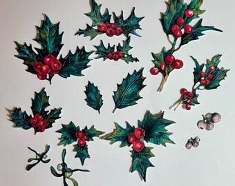 May include: A collection of holly and mistletoe cutouts. The holly features dark green leaves with red berries. The mistletoe has green leaves and small white berries. The cutouts are arranged on a white surface.