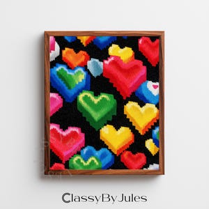 May include: A framed print with a repeating pattern of colourful, pixelated hearts on a black background. The hearts are in shades of red, yellow, green, and blue. The wooden frame surrounds the artwork. The text "ClassyBy Jules" is at the bottom.