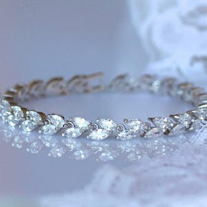 May include: A silver bracelet with a row of marquise-shaped clear stones set in a leaf design.