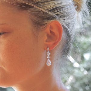 May include: Silver dangle earrings with clear pear-shaped and round cubic zirconia stones.