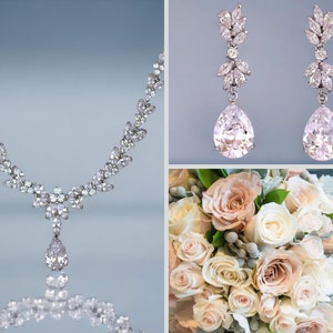 May include: A bridal jewelry set with a delicate necklace and matching earrings. The necklace features a pear-shaped pendant and a row of small stones. The earrings are also pear-shaped with a cluster of stones at the top.