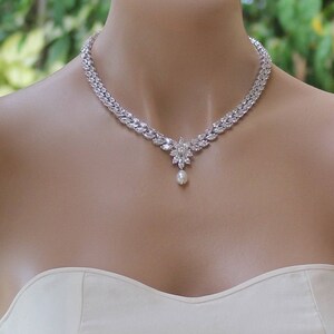 K&ouml;nnte beinhalten: Eine silberne Halskette mit einem perlmuttfarbenen Anh&auml;nger und einem floralen Design. Die Halskette besteht aus kubischen Zirkonia-Steinen und ist perfekt f&uuml;r eine Hochzeit oder einen besonderen Anlass.