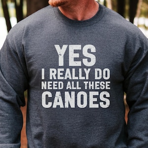 以下が含まれることがあります： フロントにYES I REALLY DO NEED ALL THESE CANOESという白いダメージ加工のテキストがプリントされた、ダークヘザーグレーのクルーネックトレーナー。長袖でリブ編みのネックラインを備えた、標準的なフィット感の衣類です。