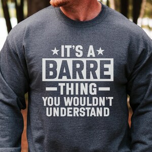 May include: A dark heather gray crewneck sweatshirt featuring white screen-printed text that reads IT'S A BARRE THING YOU WOULDN'T UNDERSTAND, with stars flanking the top line and horizontal lines separating the words BARRE and THING.