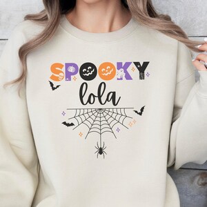 Sweat-shirt personnalisé Lola pour Halloween | Pull col rond personnalisé avec chauve-souris, toile d'araignée, citrouille et fantôme | Cadeau mignon pour l'automne et la saison des frissons