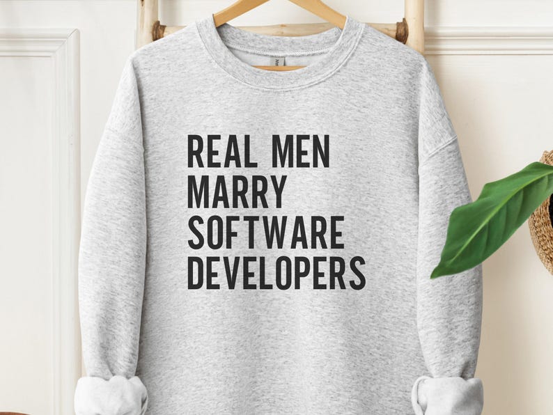 Grey sweatshirt with black text that reads "REAL MEN MARRY SOFTWARE DEVELOPERS".