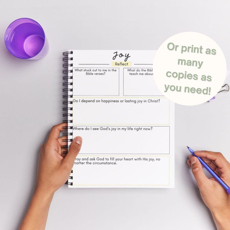 May include: A spiral-bound journal with the word "Joy" at the top, featuring prompts for reflection. The journal includes sections for Bible verses, teachings, and personal experiences. A purple cup and a pen are also visible.