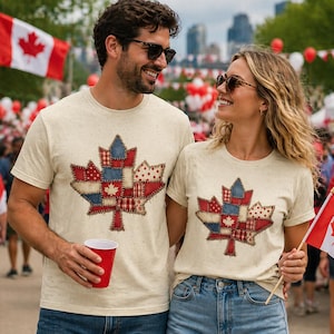 Puede incluir: Dos personas vestidas con camisetas beige a juego con un diseño de hoja de arce de retazos en rojo, blanco y azul. Una bandera canadiense es visible en el fondo, junto con una multitud de personas.