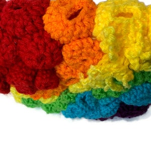 May include: A rainbow crocheted headband featuring a range of colours, including red, orange, yellow, green, blue, and purple.