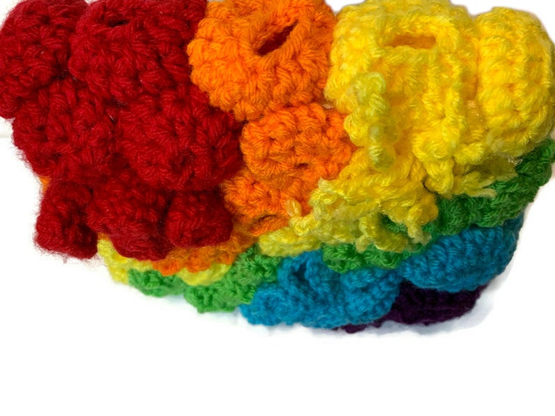 May include: A rainbow crocheted headband featuring a range of colours, including red, orange, yellow, green, blue, and purple.
