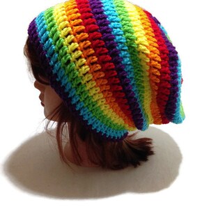 Puede incluir: Un gorro de punto de crochet a rayas de arco&iacute;ris. El gorro est&aacute; hecho con una variedad de colores, incluyendo rojo, naranja, amarillo, verde, azul, a&ntilde;il y violeta.