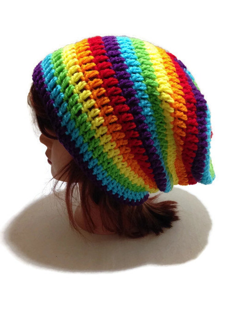 Puede incluir: Un gorro de punto de crochet a rayas de arco&iacute;ris. El gorro est&aacute; hecho con una variedad de colores, incluyendo rojo, naranja, amarillo, verde, azul, a&ntilde;il y violeta.