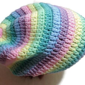 May include: A crocheted beanie hat in a rainbow color pattern of pink, yellow, green, blue, and purple.