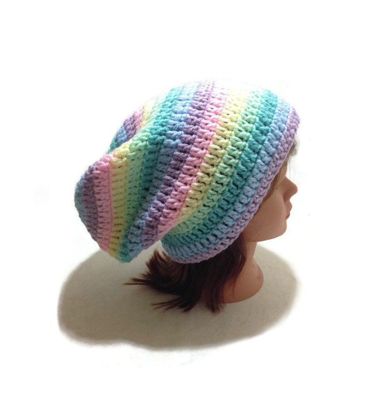 May include: A rainbow striped crochet beanie hat. The hat is made with a soft, colorful yarn and has a slouchy fit.