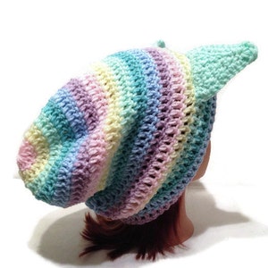 May include: A rainbow striped crochet beanie with a single, long, light blue crochet earflap.