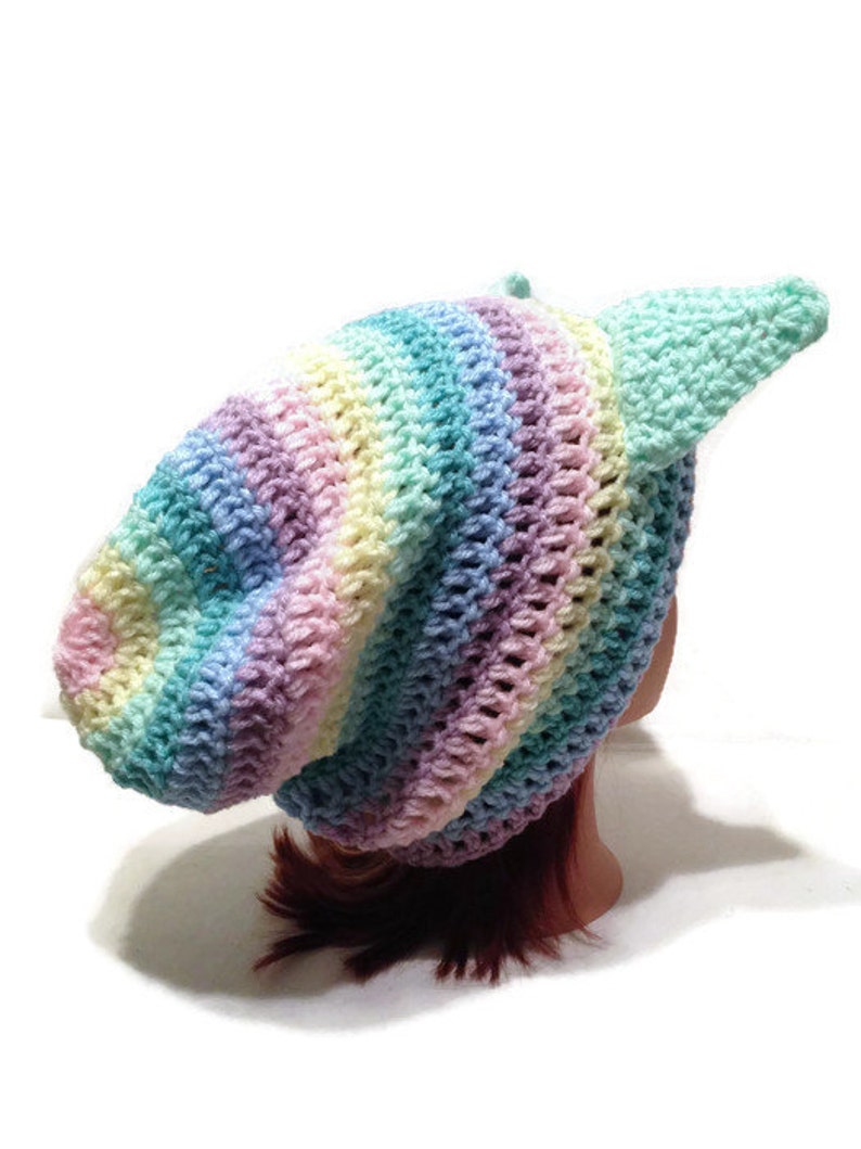 May include: A rainbow striped crochet beanie with a single, long, light blue crochet earflap.