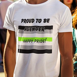 May include: White t-shirt with the text "PROUD TO BE AGENDER" above a horizontal stripe design in black, gray, and green, with "HAPPY PRIDE!" below. The shirt is short-sleeved.