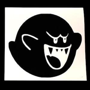 Könnte beinhalten: Ein schwarz-weißer Aufkleber mit einem Cartoon-Geist mit offenem Mund und scharfen Zähnen. Der Geist hat einen runden Körper, kleine Arme und einen bedrohlichen Ausdruck. Der Aufkleber befindet sich auf weißem Hintergrund.